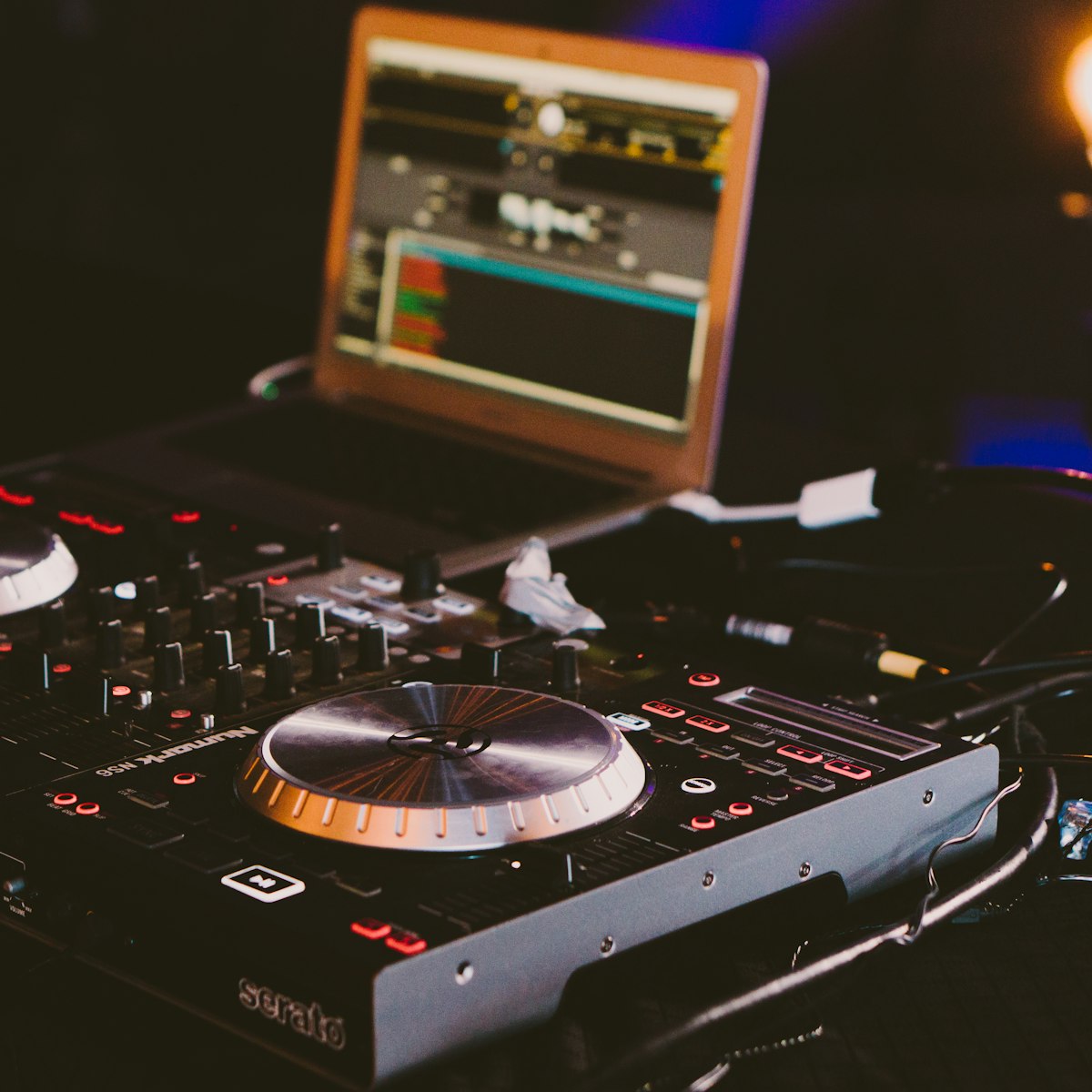 A DJ controller and laptop lit up in a dark room