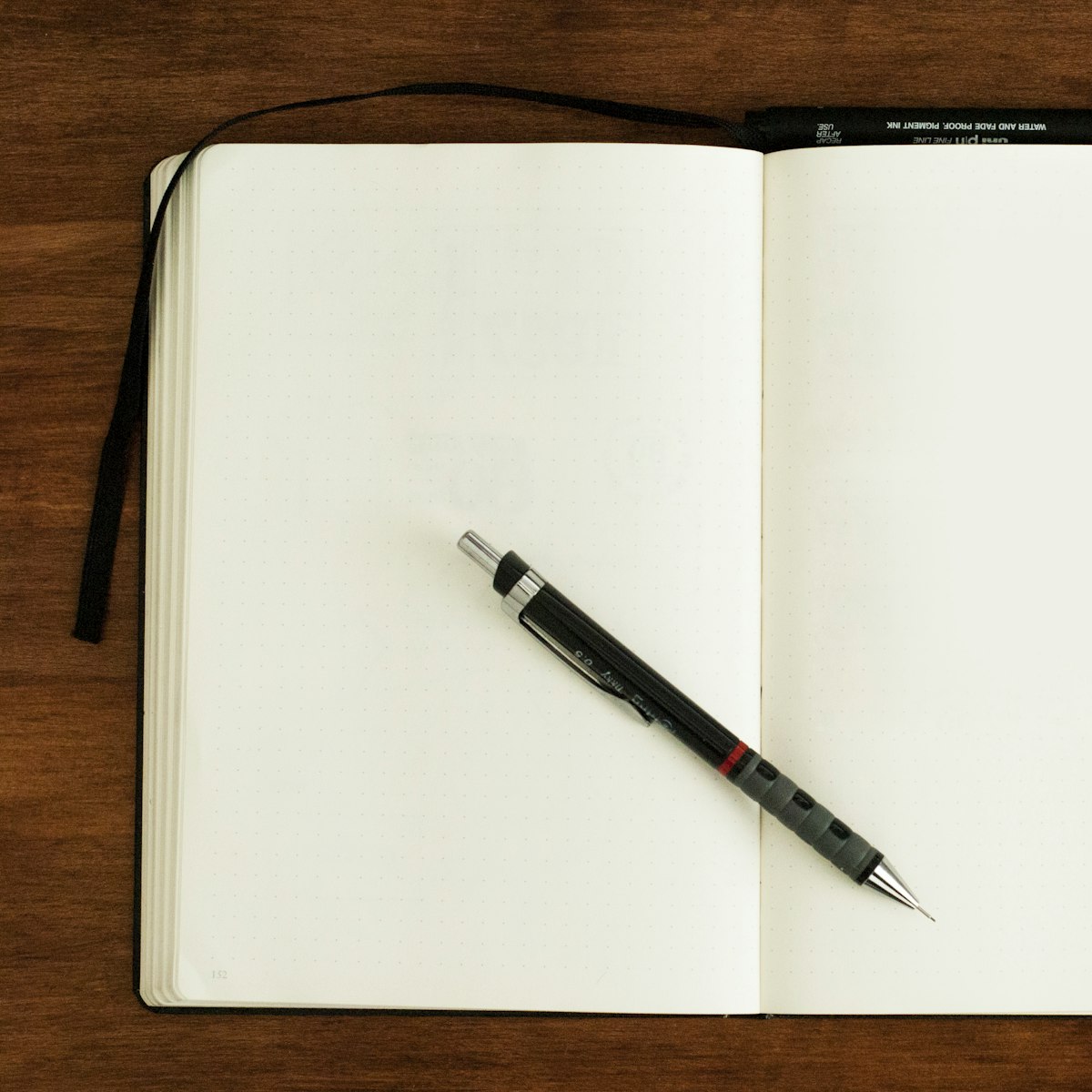 An open notebook and a pencil on a dark wooden desk