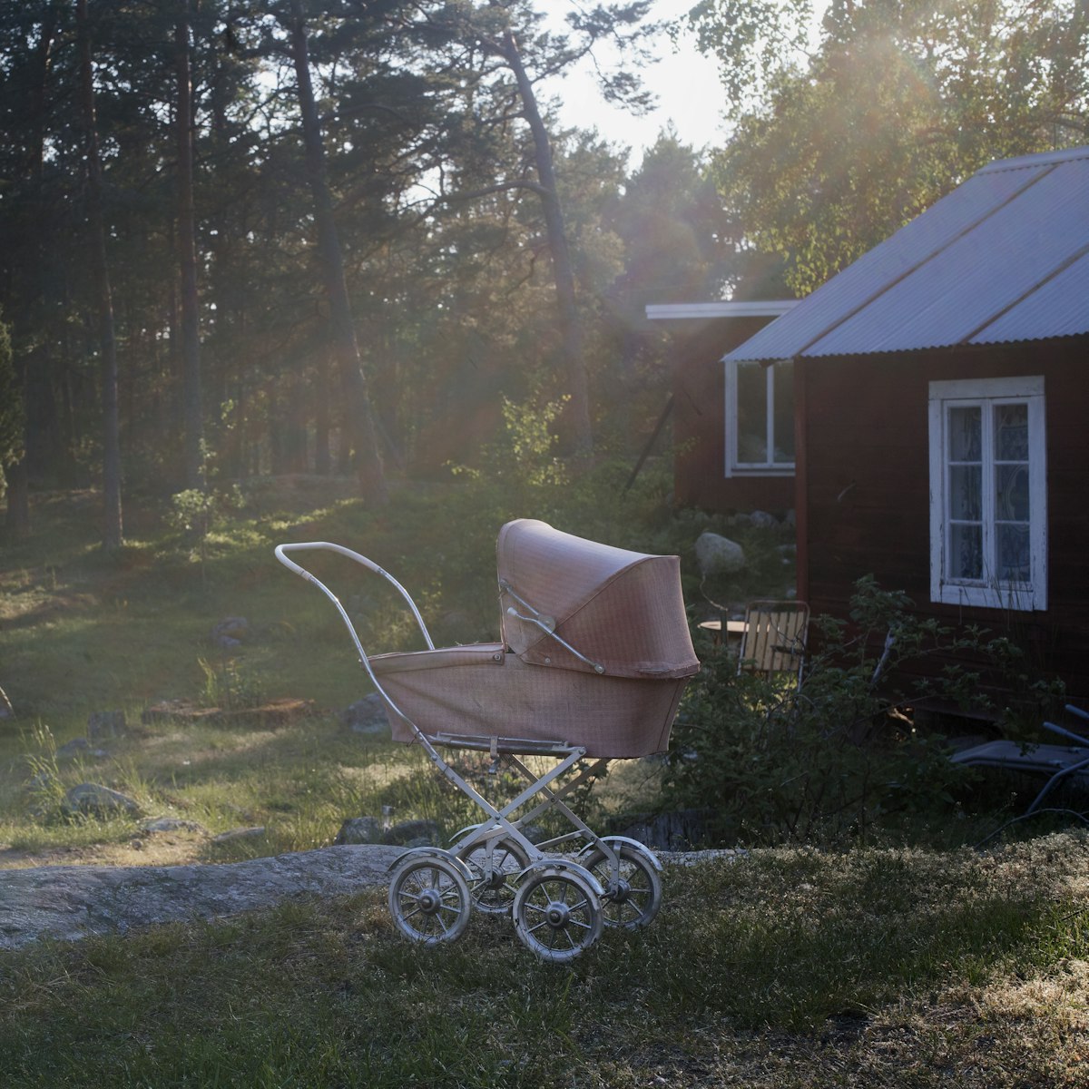 An old fashioned pram parked on a lawn in late afternoon light