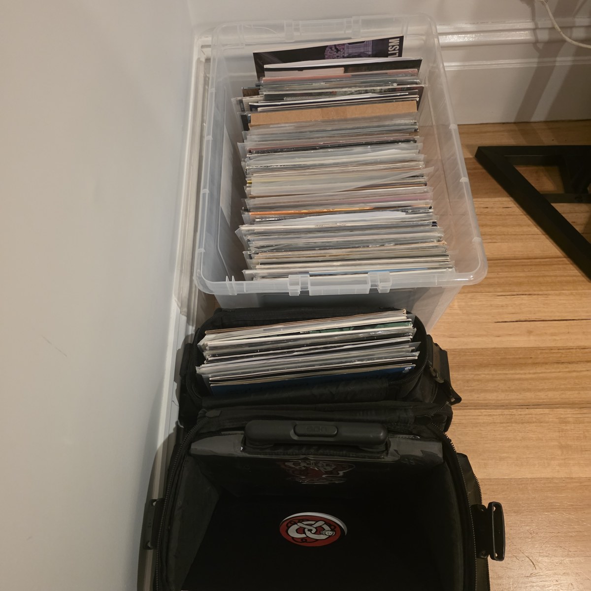 Crates of records stacked on the floor beside a record bag