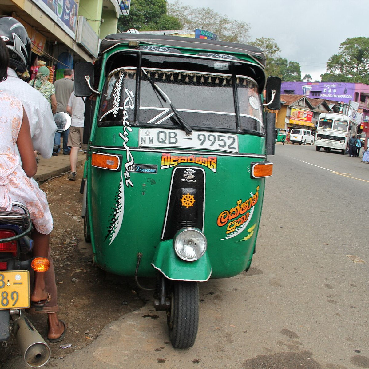A green tuk tuk parked on a Sri Lankan street