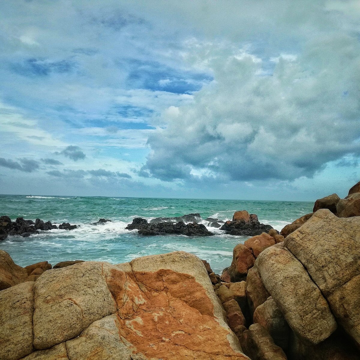 Turquoise water breaking over golden rocks on the Sri Lankan coast
